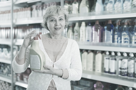 Blonde woman buyer choosing household chemical goods in the storeの写真素材