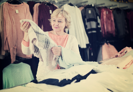 Adult female consumer choosing wool scarf in the clothes shopの写真素材