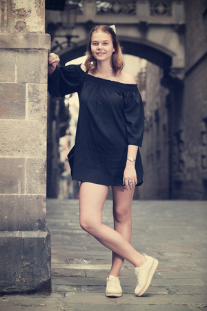 
Positive young girl standing near the stone wall at the street の写真素材