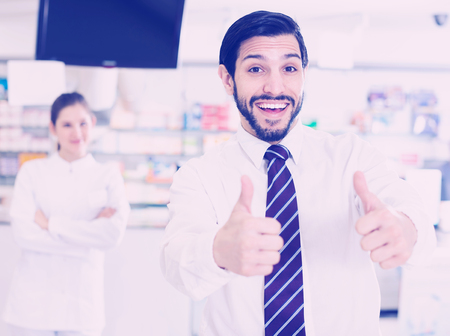 Portrait of a smiling customer male happy with the service in a modern pharmacy.の写真素材