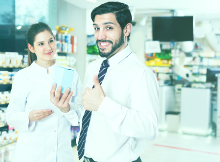 Portrait of satisfied man client with medicine in pharmacyの写真素材
