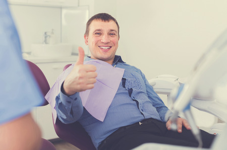 adult visitor man sitting in chair in medical center and thumbs up の写真素材