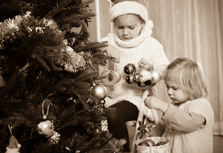 Happy european girls  putting decorations on New Year  tree in appartmentの写真素材