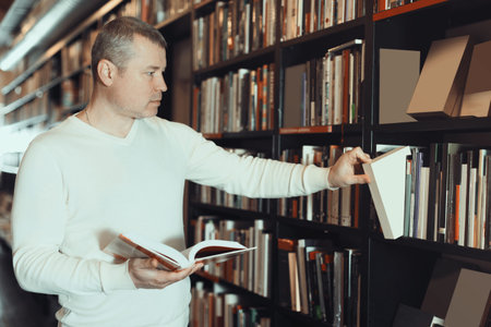 Man absorbedly looking for interesting books on rack in bookstore