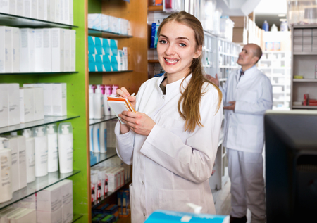Smiling beautiful  female pharmacist posing in drugstoreの写真素材