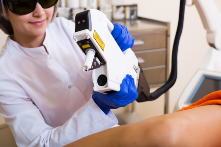 Glad female visitor having leg hair removed with laserの写真素材