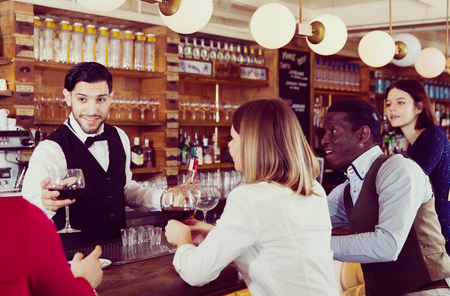 Young people are relaxing near bar counter and drinking alcohol in luxurious restaurant.の写真素材