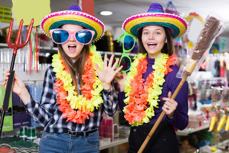 Two cheerful young female friends having fun in festival outfits store while preparing for partyの写真素材