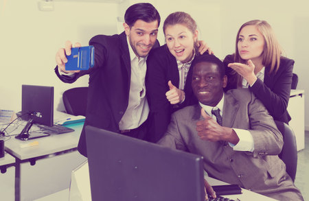 Smiling group of business people making selfie in modern office