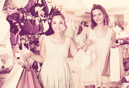 Two female are holding purchases in apparel store. の写真素材