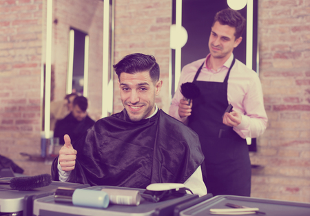 Handsome man approving result of hairdresser work, looking satisfied with his new hairdoの写真素材