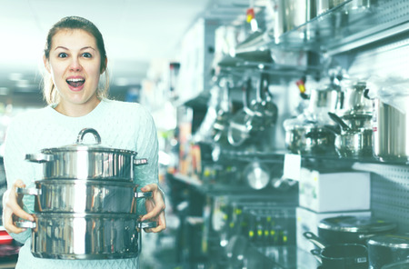 admiring woman is looking modern saucepan for her kitchen in the storeの写真素材