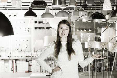 Young female  standing near modern lamp  in the  designer furniture storeの写真素材