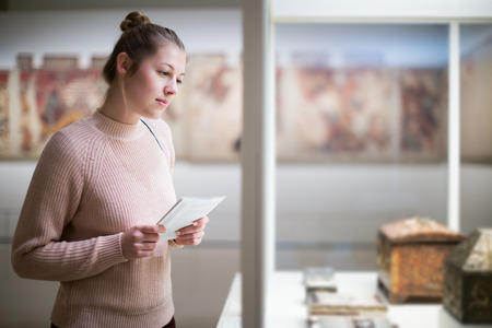 adult beauty woman standing near exposition  in art museum, using guideの写真素材