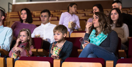 Audience eating popcorn and watching a movie at the cinemaの写真素材