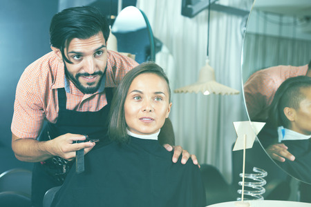 Smiling male professional with female talking about hairstyleの写真素材