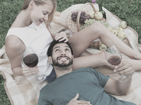 Adult happy man is lying on the lap of girlfriend in time picnic in the park.の写真素材