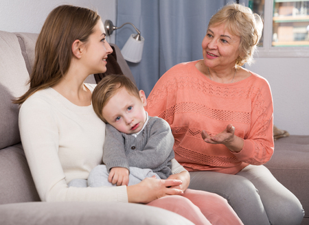 Adult female with her mother are talking about life and parenting child at home.の写真素材