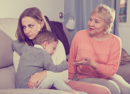 Two women are quarreling for upbringing toddler at home.の写真素材
