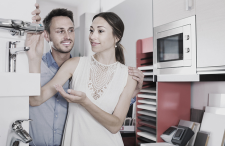 Happy family choosing faucet for kitchen in furniture workshopの写真素材