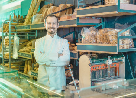 Young  positive man seller displaying assortment of bakery