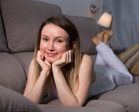 Cheerful girl is lying on sofa and playful posing at home.