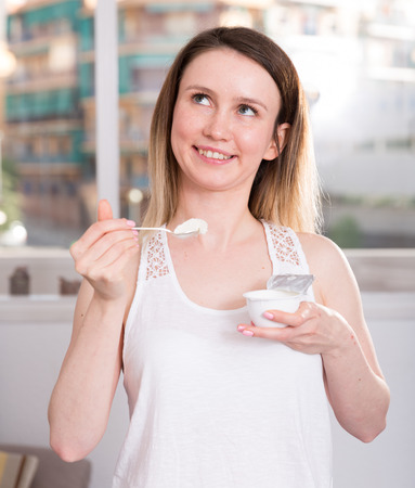 Young woman is posing with yogurt at home.の写真素材