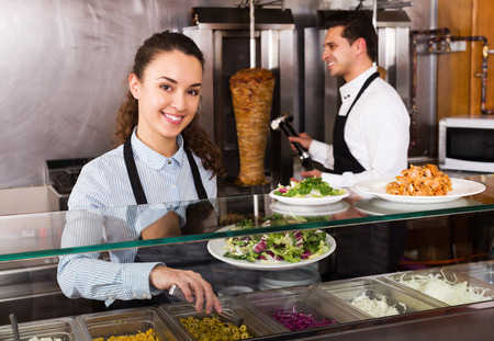 Adult attractive restaurant staff posing at kebab counter and smilingの写真素材