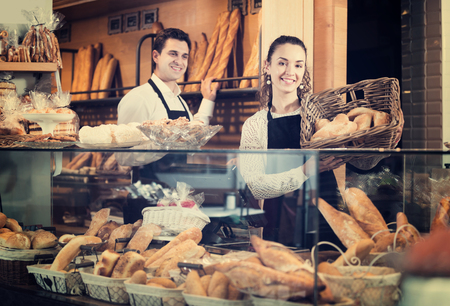 Friendly seller staff offering bread and different pastry for saleの写真素材