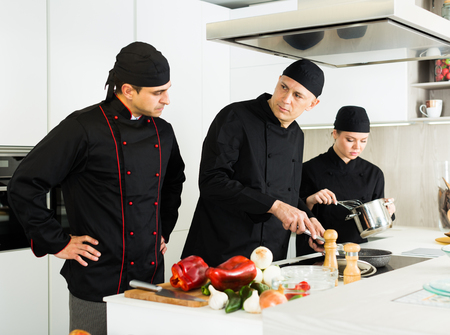Portrait of  professional chefs  in black uniform  working with vegetables on kitchen 

の写真素材