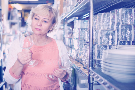 customer woman choosing crystal glass for wine in the dishes shopの写真素材