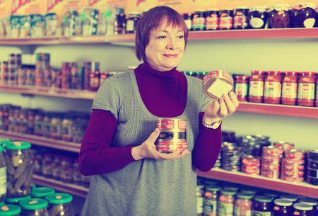 Woman customer choosing tin canned goods in the food store

の写真素材