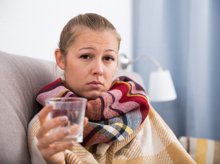 Young woman is unhealthy and drinking water at home.の写真素材