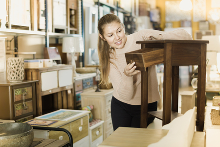 Girl customer choosing bedside in the furniture shop before the buyingの写真素材