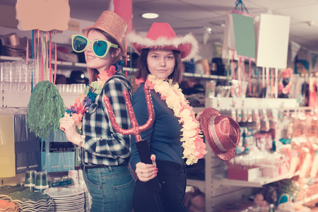 friendly girls shopping together, looking for funny things in store of festival outfits and accessoriesの写真素材