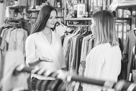 Portrait of two young women  friends talking  in  clothes shopの写真素材