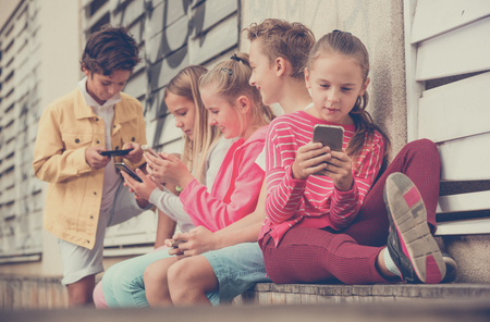 Five kids are playing on phone in the playground.の写真素材