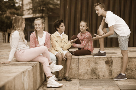 Two boys and three girls are talking about play on walk in the park.の写真素材