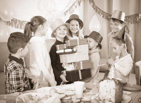 Boys and girls giving gifts to birthday girl during dinner