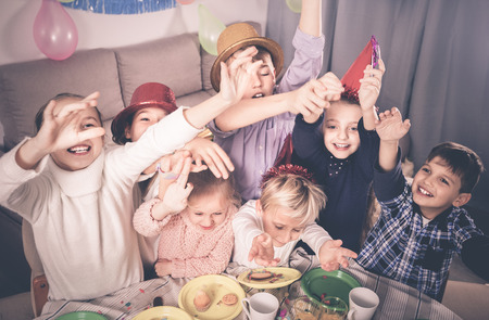 Positive smiling boys and girls behaving jokingly during friendâs birthday partyの写真素材