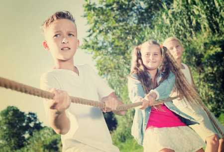 Group of laughing children having fun together outdoors pulling ropeの写真素材