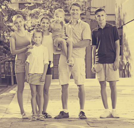 Positive parents with four children in different ages taking promenade in cityの写真素材