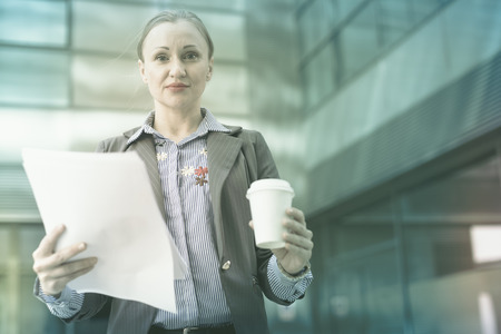 Smiling businesswoman in suit with cup of coffee in the handの写真素材