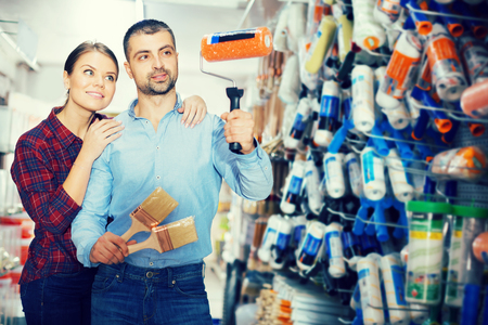 Two positive designers are holding brushes and roller for redecorate room in the shopの写真素材
