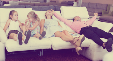Portrait of smiling family which is choosing new sofa-transformer in the store.の写真素材