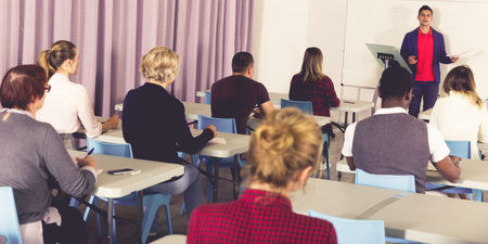 Multinational group of adult students working together with professor in auditorium