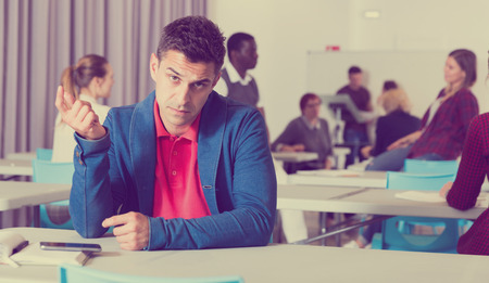 Portrait of unhappy guy sitting apart in class, having conflict with fellows students
の写真素材