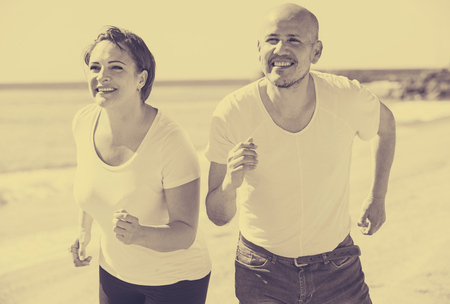 ï»¿portrait of a happy adult couple training together by the sea outdoorsの写真素材