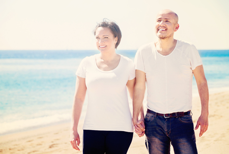 Pleasant  mature couple gladly hugging each other and enjoying the beachの写真素材