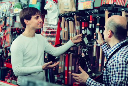 Smiling salesman showing different tools and instruments in supermarketの写真素材